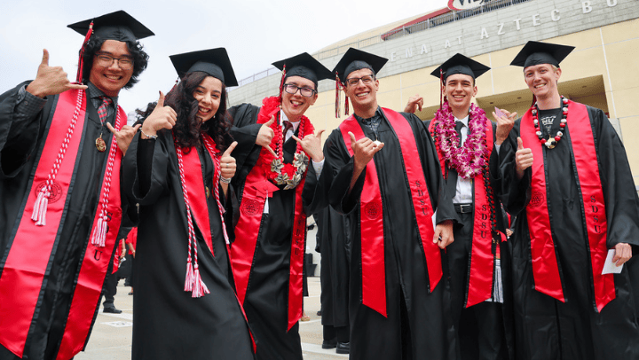 SDSU grads pose for the camera in their caps and gowns during commencement ceremonies.